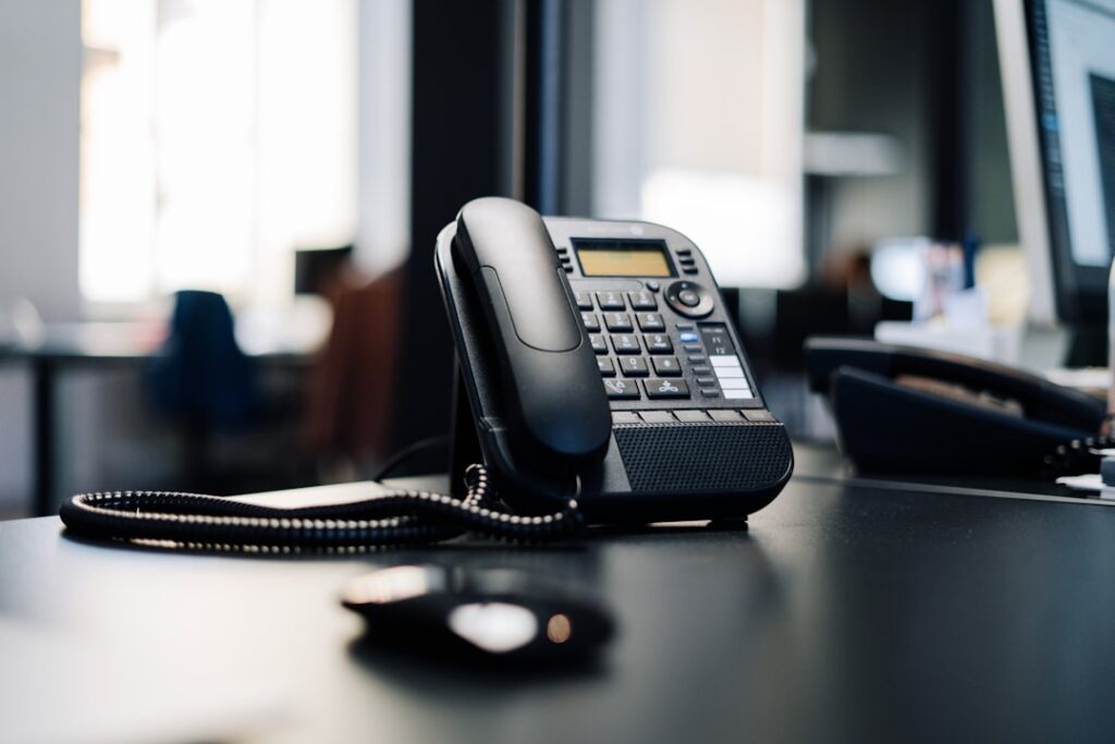 Professional business phone on modern office desk representing VoIP telecommunications services. Photo by Dkn8-zPIbwo on Unsplash